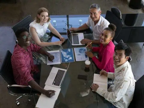 Team in overleg rond een tafel met laptops